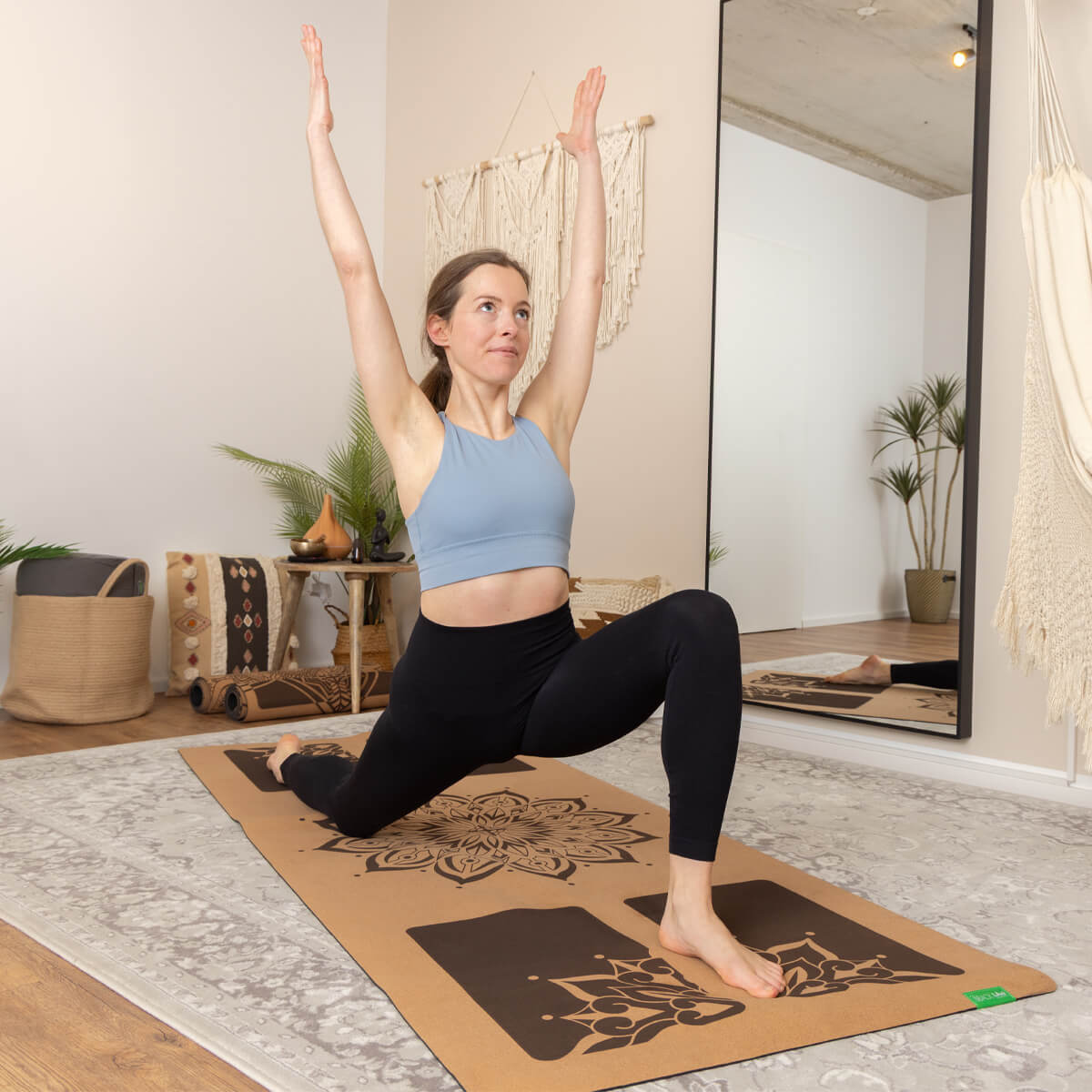 Frau praktiziert Yoga auf BACKLAXX Yogamatte mit Mandala-Design in hellem Wohnzimmer mit Spiegel, natürliches Licht durch Fenster