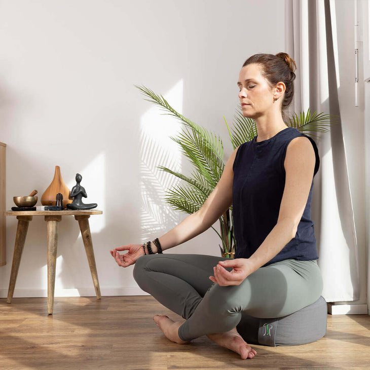 Frau in Schneidersitz auf Meditationskissen