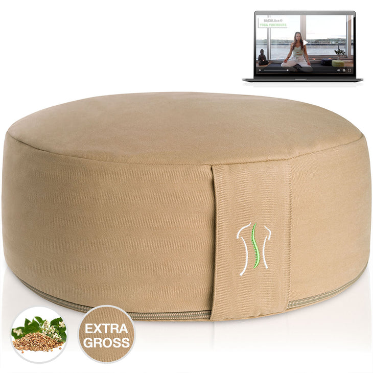 Rundes Kissen sandduenenbeige mit Naht, neben einem Laptop mit Yoga-Video
