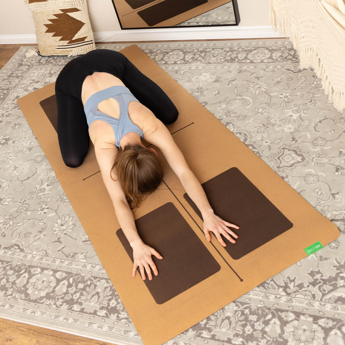 Frau in grauem Tanktop praktiziert Kindeshaltung auf NIYO LAB Kork-Yogamatte - Entspannende Pose mit Ausrichtungslinien für korrekte Haltung
