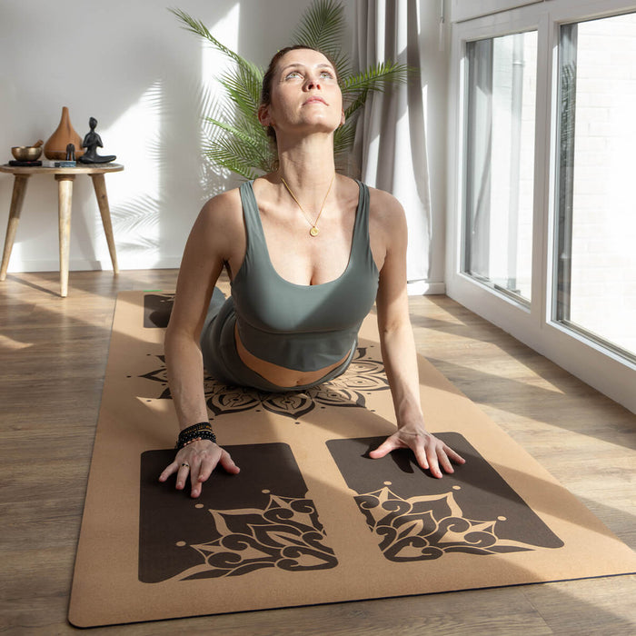 Frau praktiziert Upward-Facing Dog auf dekorativer Yogamatte mit floralem Design - Entspannte Yogapraxis im lichtdurchfluteten Raum mit Buddha-Statue
