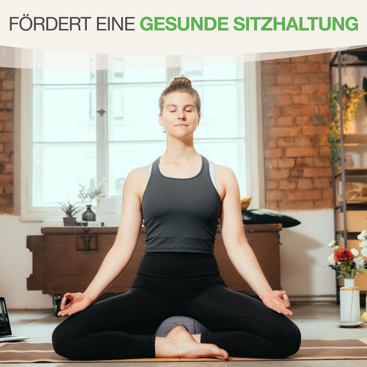 BACKLAXX Yogakissen fördert eine gesunde Sitzhaltung - Frau praktiziert Meditation im Lotussitz mit Mudra-Gesten in atmosphärischem Raum mit Backsteinwänden
