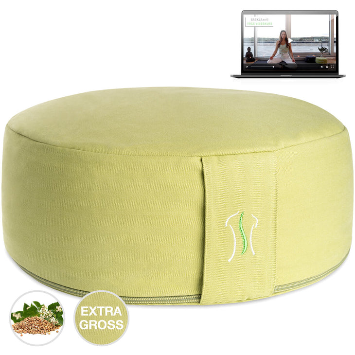 Rundes Kissen limettengruen mit Naht, neben einem Laptop mit Yoga-Video
