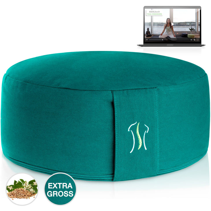 Rundes Kissen smaragdgruen mit Naht, neben einem Laptop mit Yoga-Video
